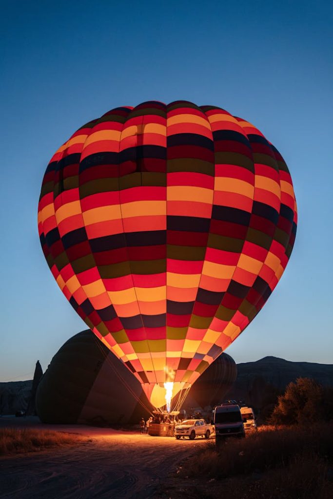 Illuminated hot air balloon ready for flight at sunset in Nevşehir, Türkiye, capturing adventure and leisure.